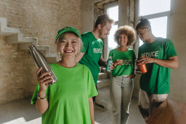 Lächelnde Aktivisten mit wiederverwendbaren Flaschen in der Wohnung - YTF01320