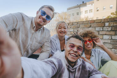 Smiling man taking selfie with friends on rooftop - YTF01337