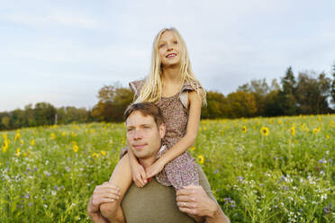 Lächelnder Vater trägt seine Tochter auf den Schultern in einem Feld - NJAF00612