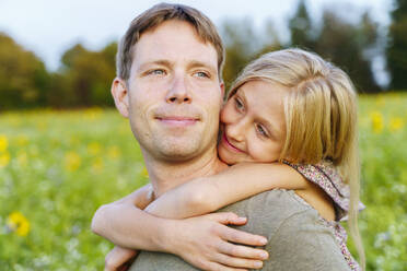 Smiling daughter embracing father in field - NJAF00613