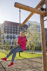 Girl playing on swing at playground - LESF00502