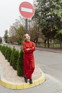 Nachdenkliche Frau vor einem Stoppschild an der Straße stehend - OSF02316