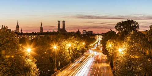 Germany, Bavaria, Munich, Vehicle light trails along illuminated city road at dusk - WDF07430
