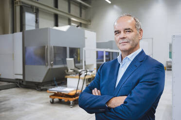 Senior businessman with arms crossed standing in factory - DIGF20963