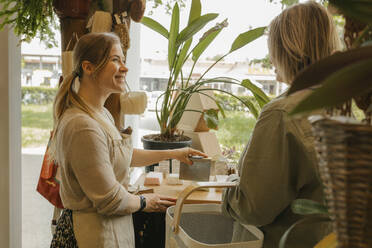 Smiling owner helping customer for cutting soap bar in store - VIVF01149