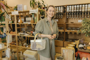 Smiling blond woman with shopping basket in zero waste store - VIVF01175