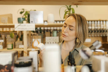Blond woman choosing beauty products in store - VIVF01185