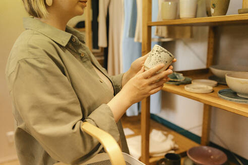 Frau wählt Keramikglas im Bioladen aus - VIVF01198