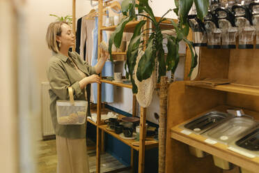 Blonde Frau wählt im Zero-Waste-Laden Keramik aus - VIVF01199
