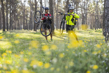 Glückliche Freunde beim Abholen von Fahrrädern im Wald - JCCMF10877