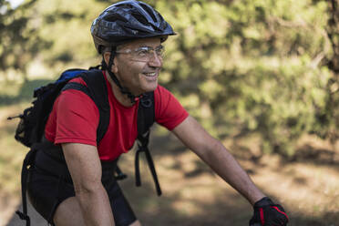 Lächelnder Mann mit Helm und Fahrrad im Wald - JCCMF10882