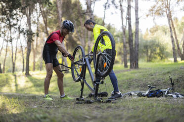 Glückliche Freunde reparieren Fahrrad im Wald - JCCMF10892