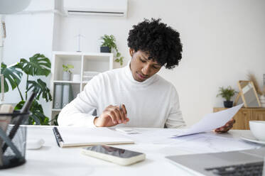 Businessman using calculator on desk at home office - ALKF00772