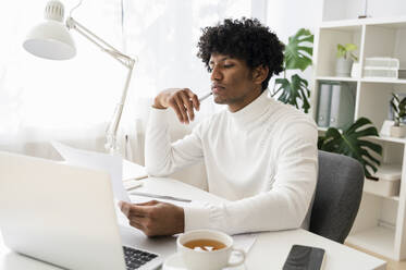 Focused businessman reading documents at desk - ALKF00778