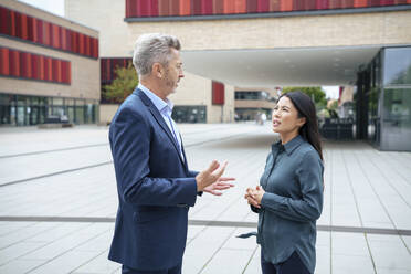 Businessman discussing with businesswoman in office park - JOSEF21937