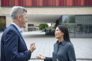 Businesswoman discussing with colleague near office building - JOSEF21938