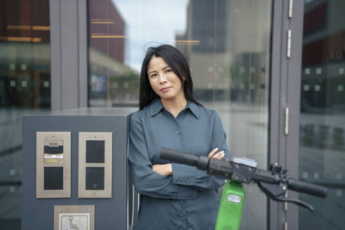 Lächelnde Geschäftsfrau in der Nähe eines Fahrrad-Sharing-Systems - JOSEF21952