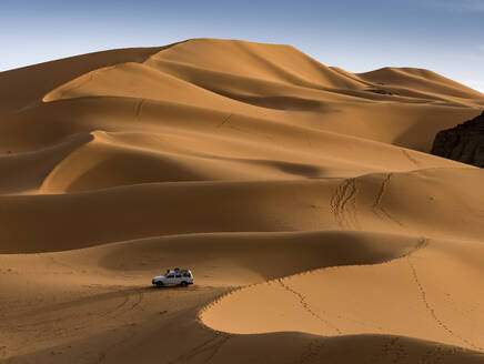 Luftaufnahme eines Geländewagens in den Sanddünen bei Sonnenuntergang in der Wüste Sahara, Djanet, Algerien, Afrika. - AAEF22942
