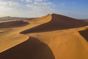 Sand dunes at sunset in the Wahiba Sands desert with clouds in the