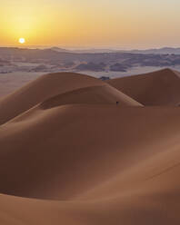 Luftaufnahme eines Spaziergängers auf den Sanddünen bei Sonnenuntergang in der Wüste Sahara, Djanet, Algerien, Afrika. - AAEF22959