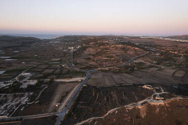 Aerial view of a road across the countryside at sunset, Mgarr, Malta. - AAEF23149