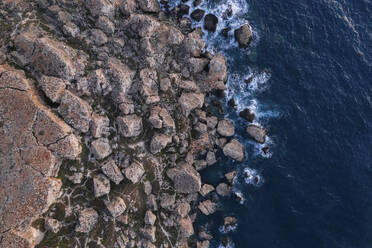 Luftaufnahme der Wellen, die auf die Felsen entlang der Küste von Il Qarraba treffen, Qarraba Bay bei Sonnenuntergang, Mgarr, Malta. - AAEF23159