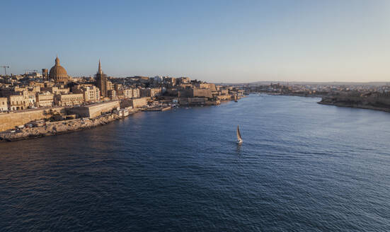 Luftaufnahme eines kleinen Segelboots entlang der Bucht in der Innenstadt von La Valletta bei Sonnenuntergang, Malta. - AAEF23166