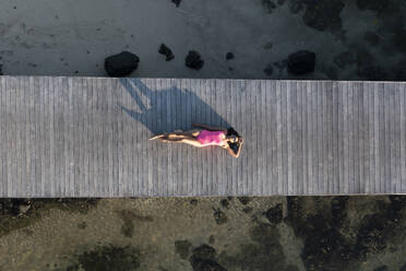 Luftaufnahme einer Frau, die sich auf dem Steg entlang der Küste hinlegt, Poste de Flacq, Bezirk Flacq, Mauritius. - AAEF23243