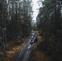 Aerial view of a car in moody forest on a muddy road, Lahemaa National Park, Harjumaa, Estonia. - AAEF23297