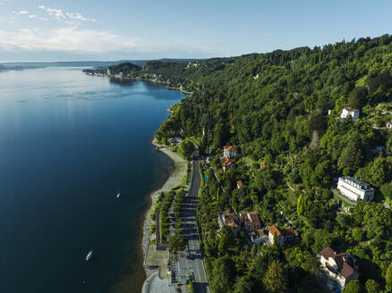 Luftaufnahme einer Straße entlang der Küste mit vertäuten Segelbooten am Lago Maggiore (Lago Maggiore) bei Sonnenaufgang, Novara, Piemont, Italien. - AAEF23345