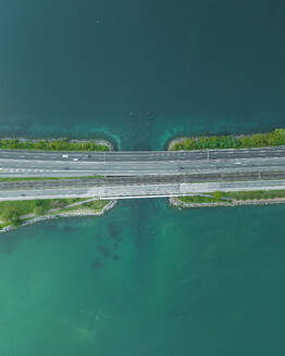 Aerial view of vehicles driving on a road crossing the Lugano lake, Melide, Ticino, Switzerland. - AAEF23476