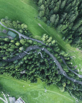 Aerial view of a small river among trees along the mountain crest in Ortisei, a small village on the Dolomites Trentino, South Tyrol in Northern Italy. - AAEF23539