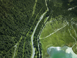 Aerial view of a road following the Dobbiaco Lake coastline on the Dolomites mountain range, Toblach, Trentino, South Tyrol, Italy. - AAEF23630