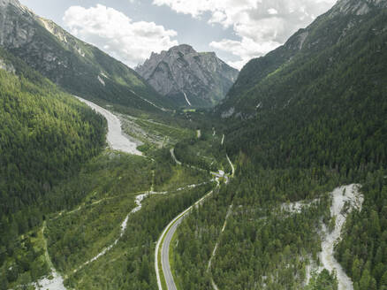 Aerial view of a road crossing the valley across Tre Cime Natural park (Drei Zinnen) with Monte Cristallo in background on the Dolomites area, Trentino, South Tyrol, Italy. - AAEF23660