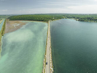 Luftaufnahme von Fahrzeugen auf einer Straße, die die Lagune Mirna und den Fluss Mirna überquert, Antenal, Istrien, Kroatien. - AAEF23796