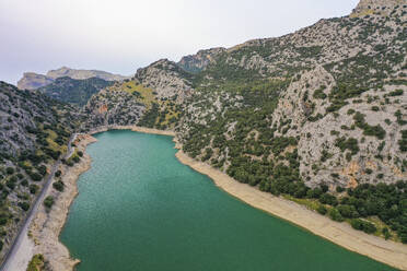 Luftaufnahme des Staudamms des Flusses Torrent de Gorg Blau mit seinem grünen Wasser, den Bergfelsen und der ihn umgebenden Vegetation in Escorca, Balearen, Spanien. - AAEF23823