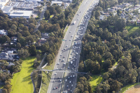 Luftaufnahme einer Autobahn inmitten einer malerischen Landschaft mit Parks und Wohnhäusern, Victoria, Australien. - AAEF23860
