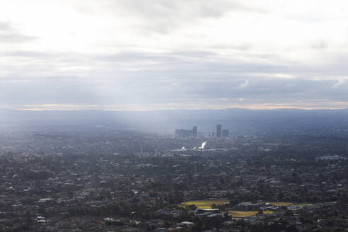 Luftaufnahme von Sonnenlicht, das durch die Wolken über den Apartments bricht, Victoria, Australien. - AAEF23869