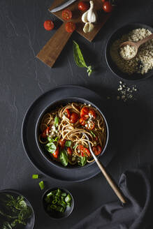Bowl of vegan wholemeal spelt spaghetti with tomatoes, basil, scallion and cashew Parmesan - EVGF04395