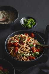 Bowl of vegan wholemeal spelt spaghetti with tomatoes, basil, scallion and cashew Parmesan - EVGF04396