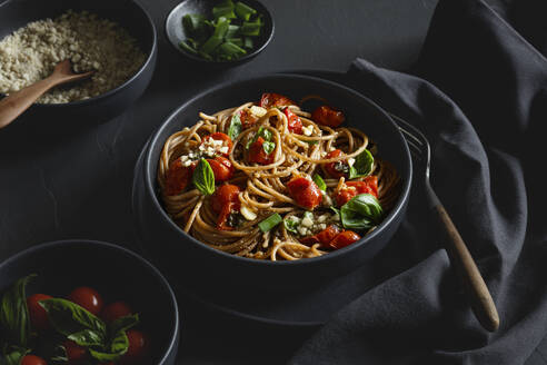 Bowl of vegan wholemeal spelt spaghetti with tomatoes, basil, scallion and cashew Parmesan - EVGF04397