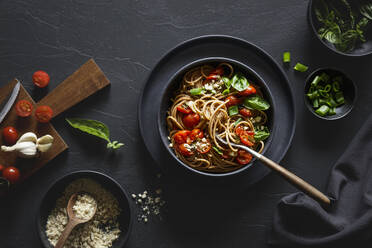 Bowl of vegan wholemeal spelt spaghetti with tomatoes, basil, scallion and cashew Parmesan - EVGF04398