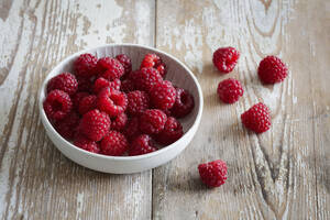 Schale mit frischen Himbeeren auf Holzunterlage - EVGF04405