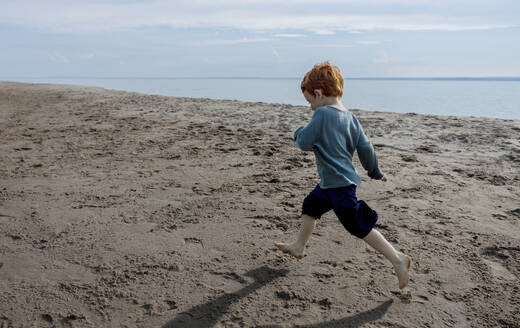 Verspielter Junge läuft auf Sand am Strand - MBLF00116