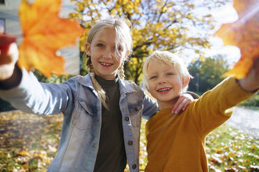 Verspielte Schwester und Bruder zeigen Blätter im Herbst Park - NJAF00618