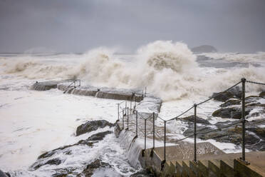 UK, Scotland, North Berwick, Waves splashing against coastal steps during Storm Babet - SMAF02635