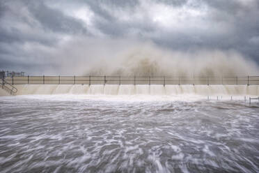 UK, Scotland, North Berwick, Long exposure of waves breaking over harbor wall during Storm Babet - SMAF02641