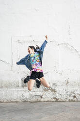 Young woman jumping in front of white wall - SVCF00392
