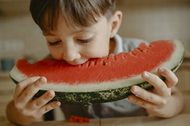 Boy eating slice of watermelon at home - ANAF02400