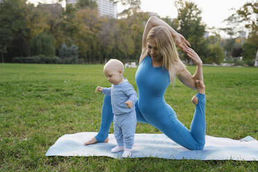 Blonde Mutter macht Stretching-Übung mit Kleinkind Sohn im Park - YBF00285